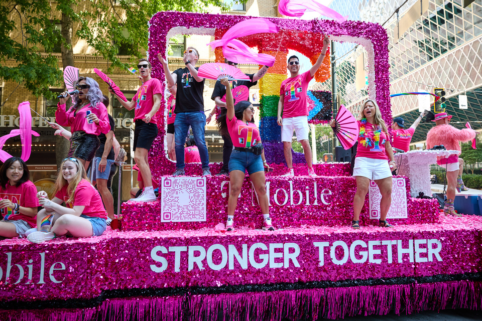 Photo of around 20 T-Mobile employees dancing on a T-Mobile "Stronger Together" Pride parade float