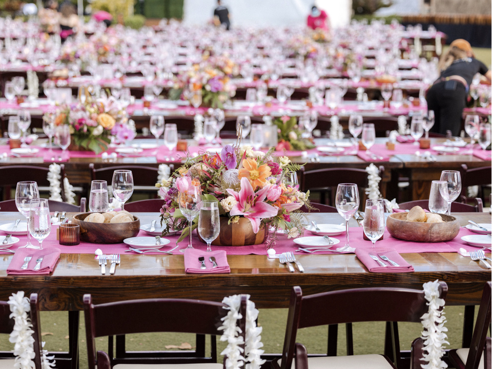 Photo of many rows of tables with tropical magenta place settings