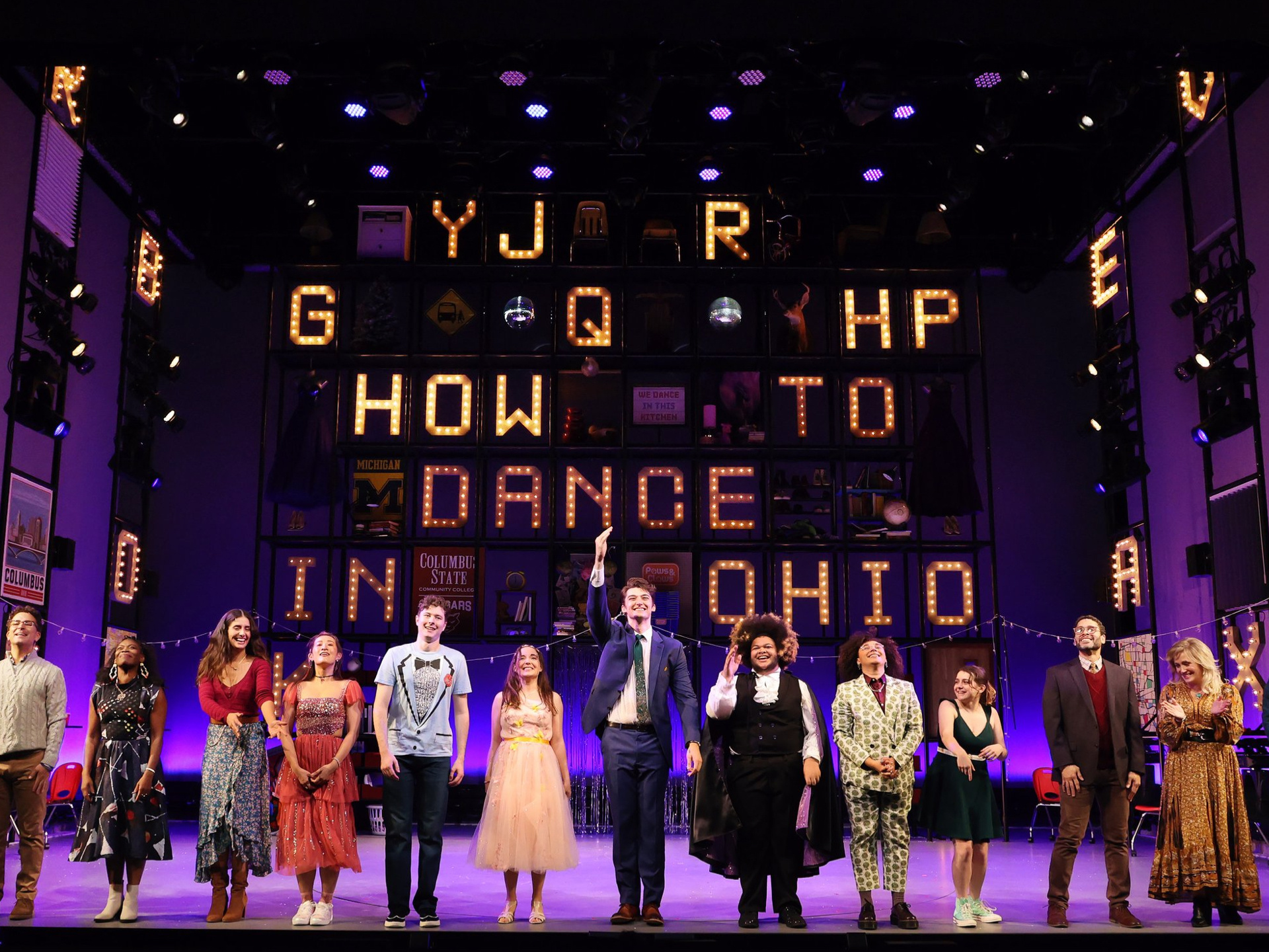 image of 12 actors on a stage preparing to take a bow. Set is purple with lit text: How to dance in Ohio, and other miscellaneous letters