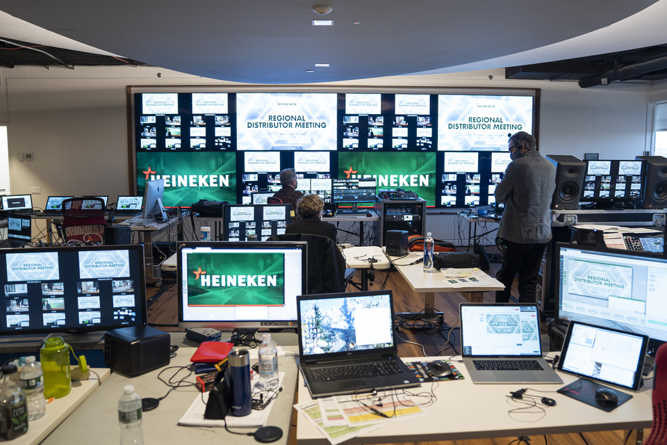 Photo shows Behind the scenes of a show of computer monitors with TVs displayed in the front. Screens show Heineken branding