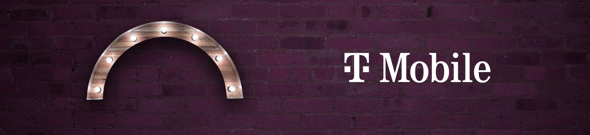 Marquee-style arch Proscenium logo and T-Mobile logo on a plum-colored brick wall background.