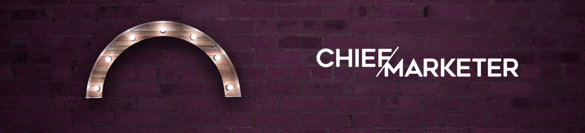 Marquee-style arch Proscenium logo and chief marketer logo on a plum-colored brick wall background.