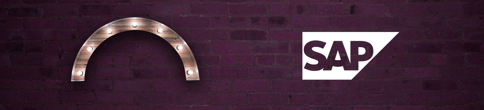 Marquee-style arch Proscenium logo and SAP logo on a plum-colored brick wall background.