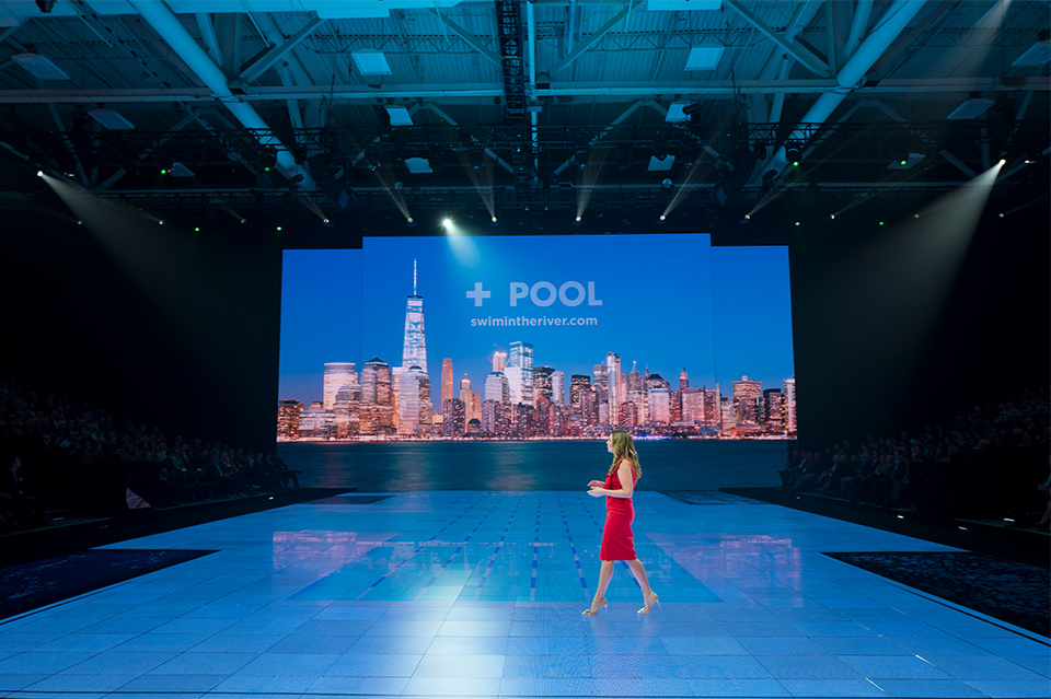 Photo of presenter on a pool/swimming themed LED screen