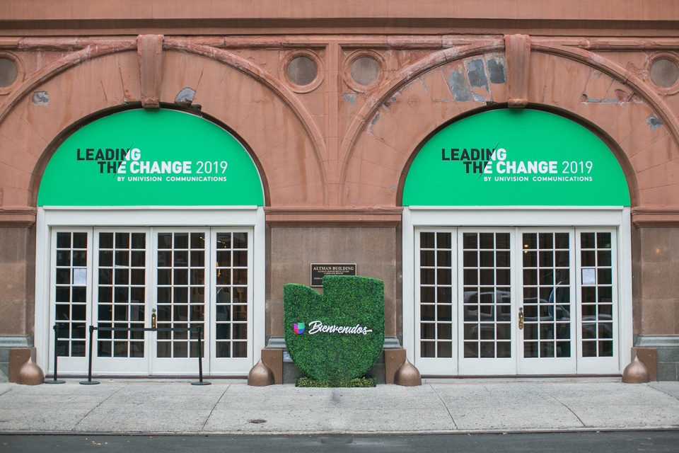 Exterior image of 2 Outside Doors with green signs above the doors reading "Leading the Change 2019 by Univision Communications."