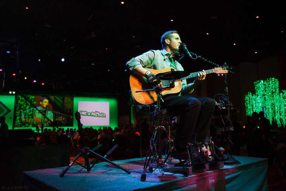 Photo of a Guitarist performing Center Stage on a Platform with green lighting in the background
