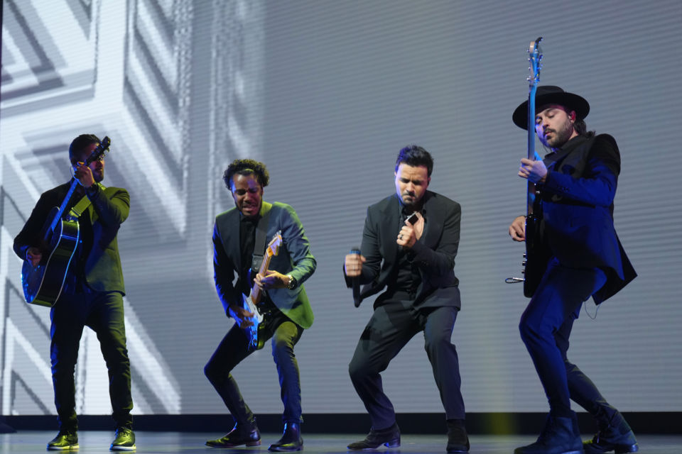 Photo of a band of 4 musicians performing on stage.